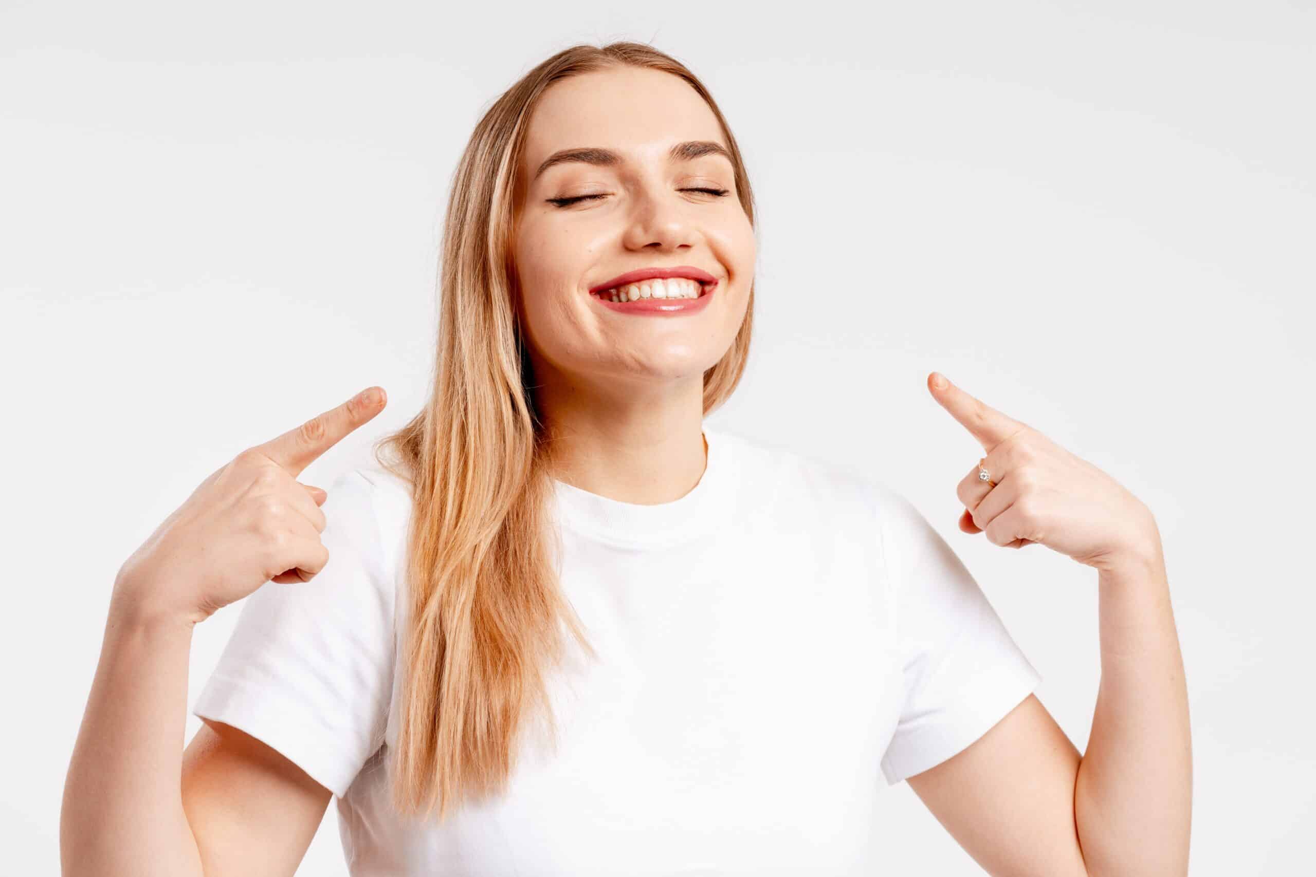 Blonde,Woman,Pointing,At,Her,Perfect,Teeth,,Showing,A,Healthy